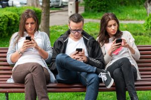 Focused group of friends looking on their phones and not sociali